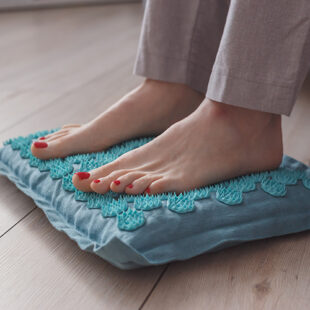 Female feet standing on acupressure mat. Self acupuncture massage. Woman having alternative medicine treatment.